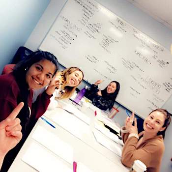 Students at a table pointing to a whiteboard